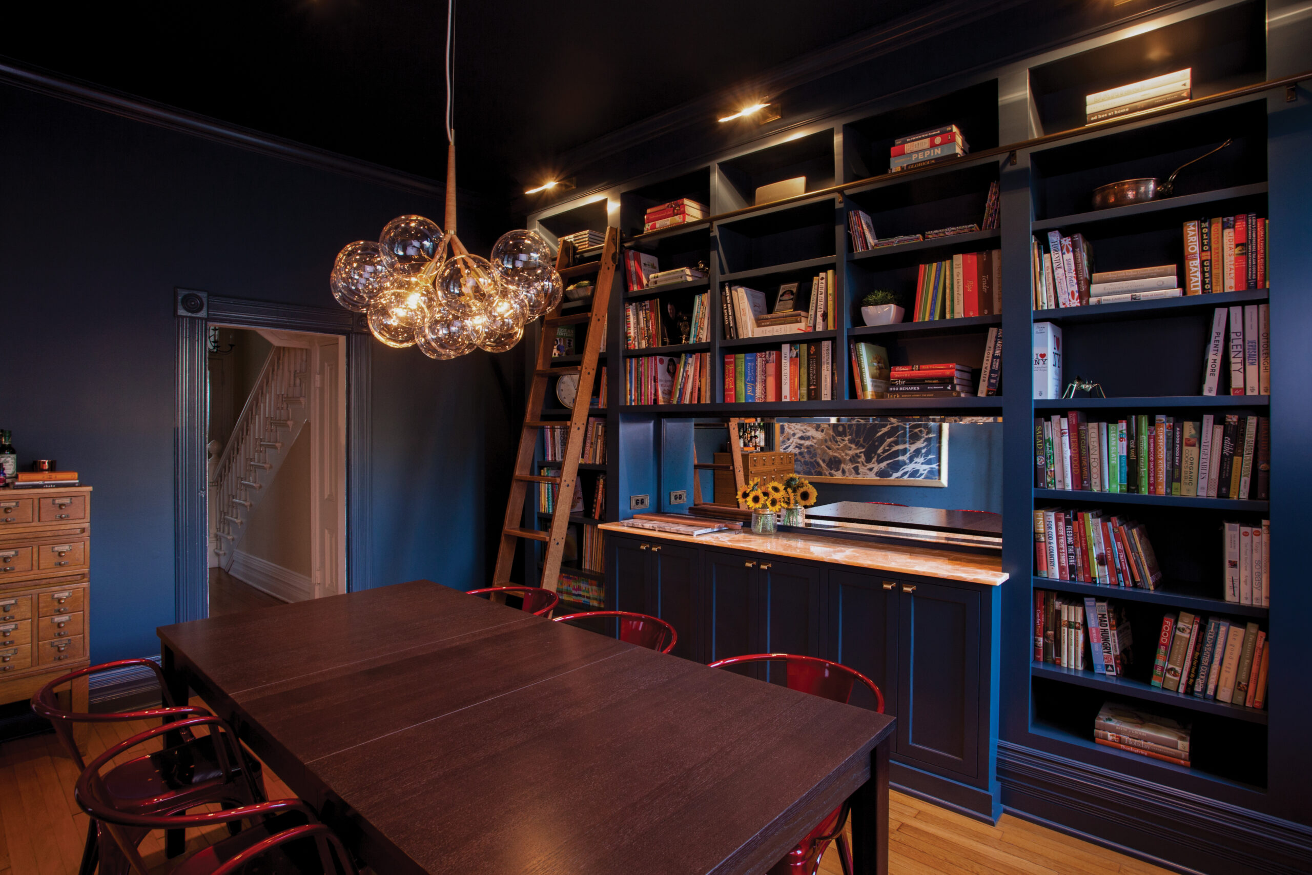 Dark blue dining, built-in library, gleaming chandelier. Twin Cities remodel.