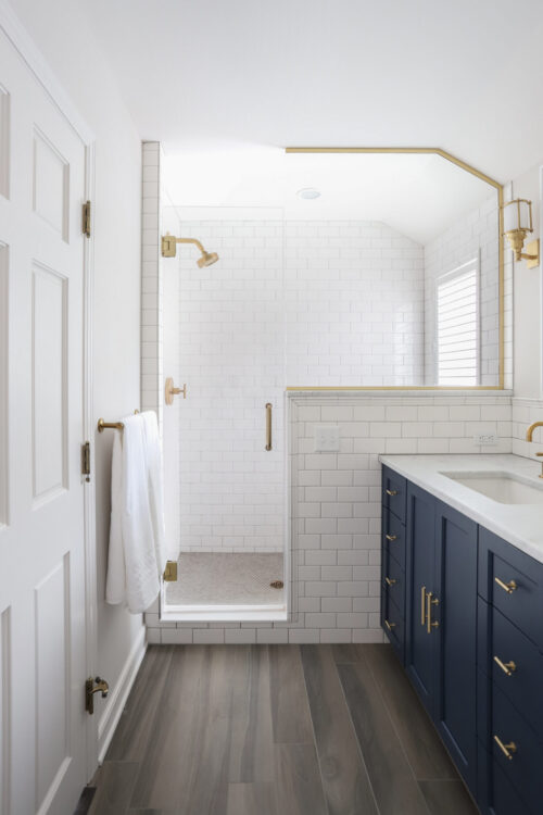 Twin Cities bathroom renovation expertly integrates white-tiled navy-cabinetry brassware.