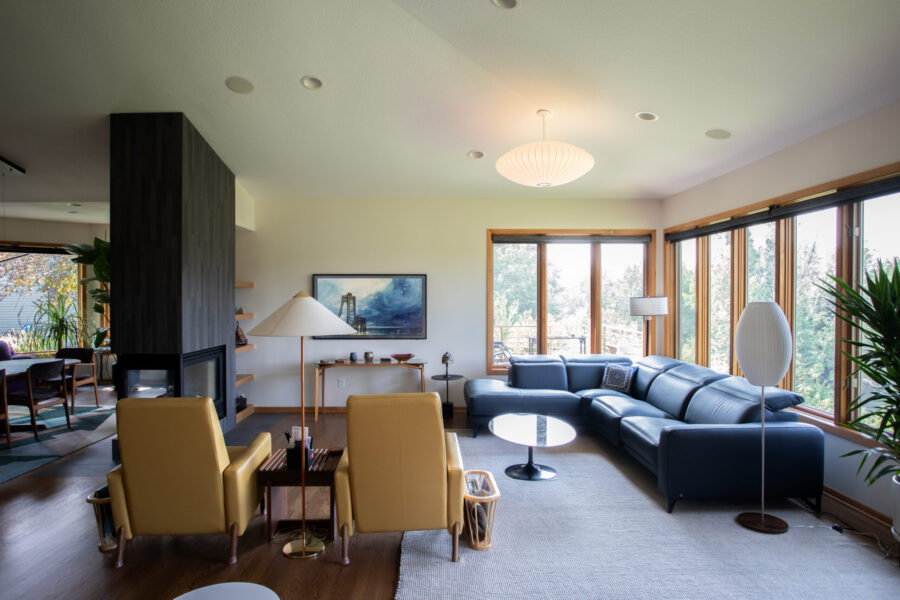 Twin Cities living room remodel features a blue sectional, yellow armchairs, dark fireplace, and abundant natural light.