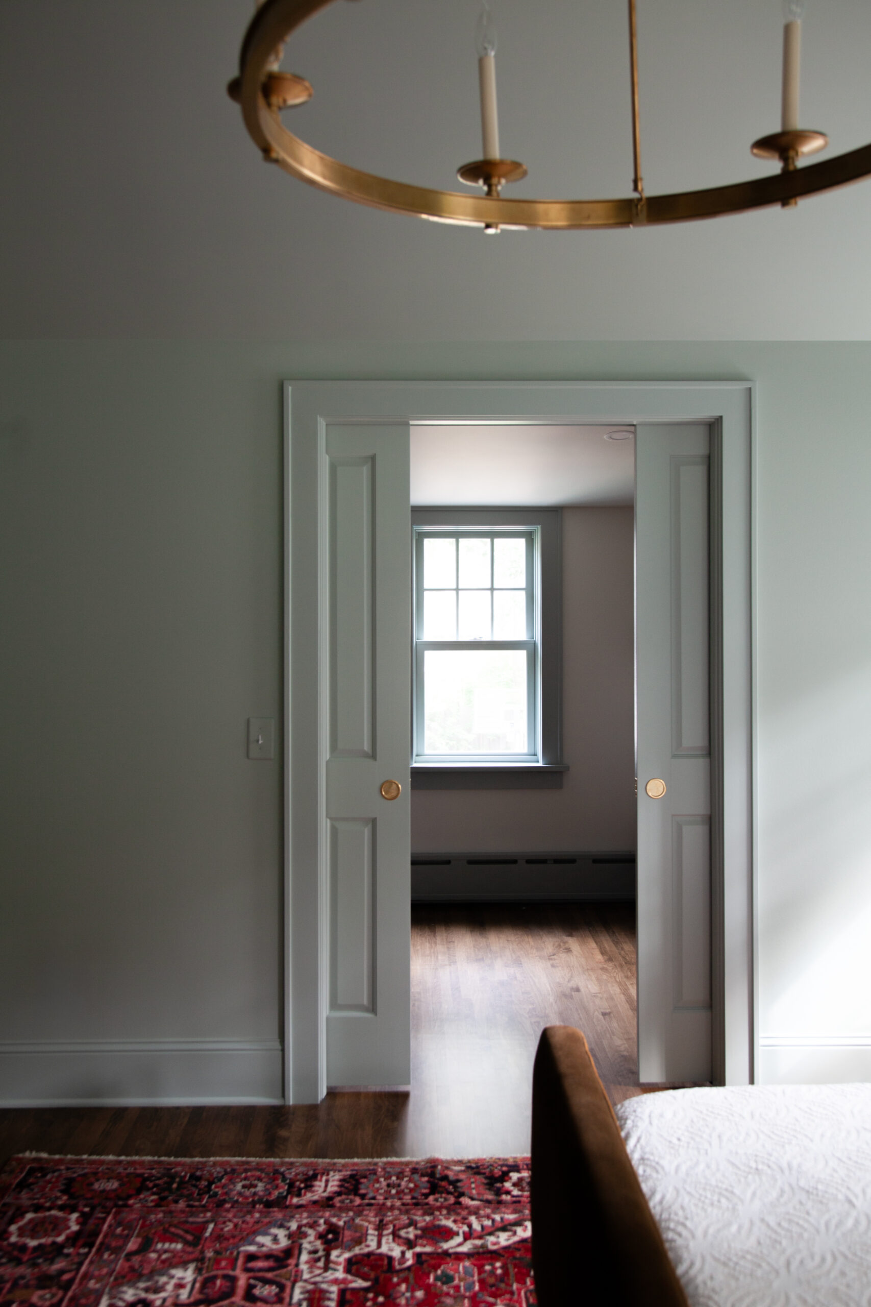 Antique-chandelier illuminates painted-panel pocket-doors, quarter-sawn-oak floorboards.