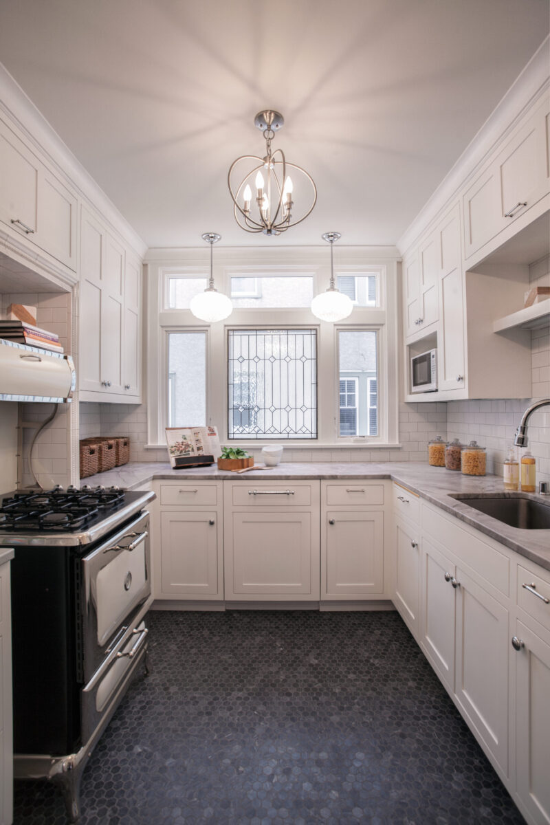 This Twin Cities kitchen renovation combines white panel cabinets, gray marble counters, dark hex floor tiles, and a vintage range.