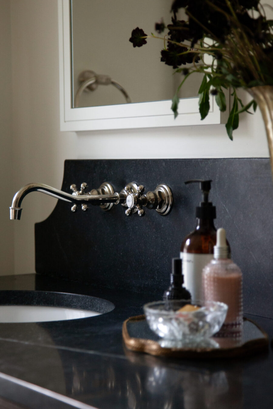 Sophisticated Twin Cities bathroom remodel offers a dark stone vanity, integrated sink, and chrome wall-mounted faucet.