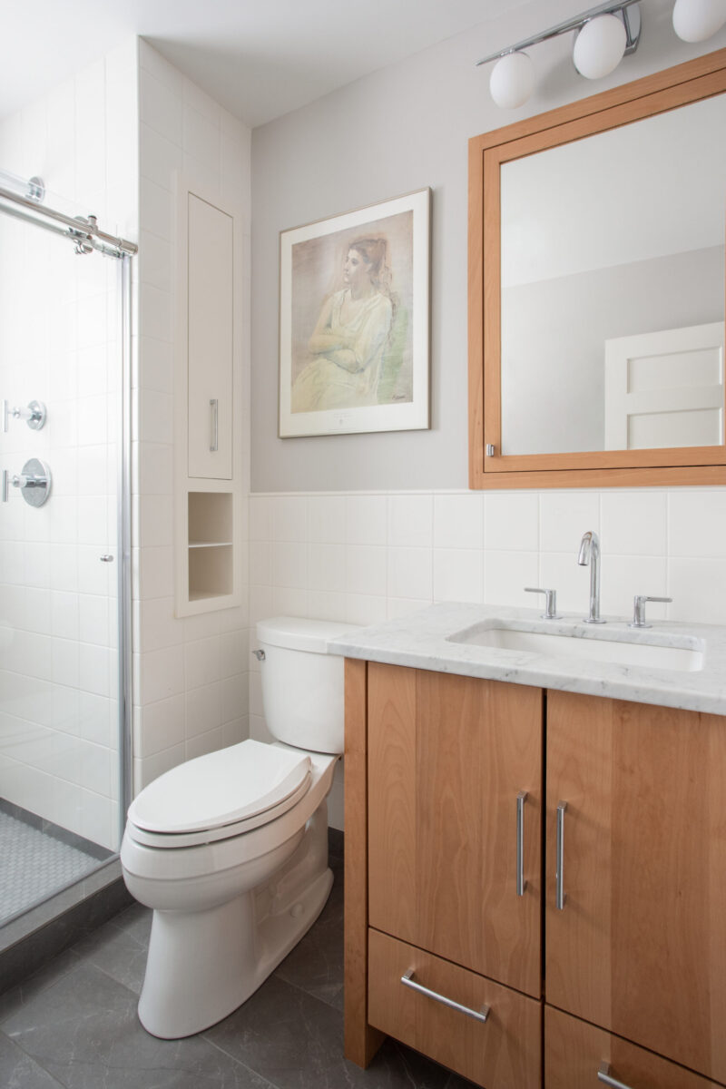 Bathroom remodel integrates handsome wood vanity, marble, and glass shower.