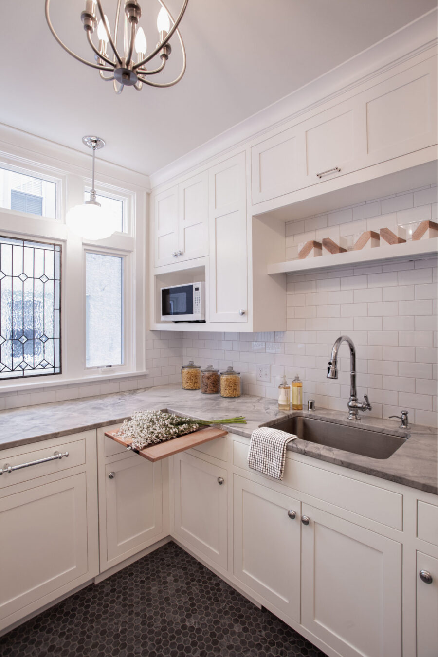 Bright Twin Cities kitchen remodel features white shaker cabinets, gray marble counters, subway tile, dark hex floor.
