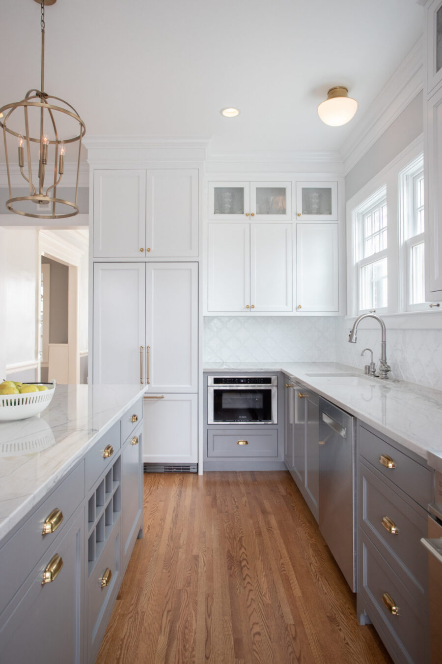 Twin Cities kitchen remodel combines bright white and gray cabinets, marble counters, warm wood floors.