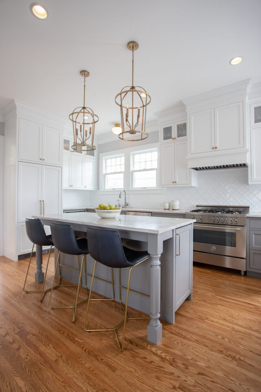 Twin Cities kitchen remodel features white cabinets, a gray island, and gold pendants.