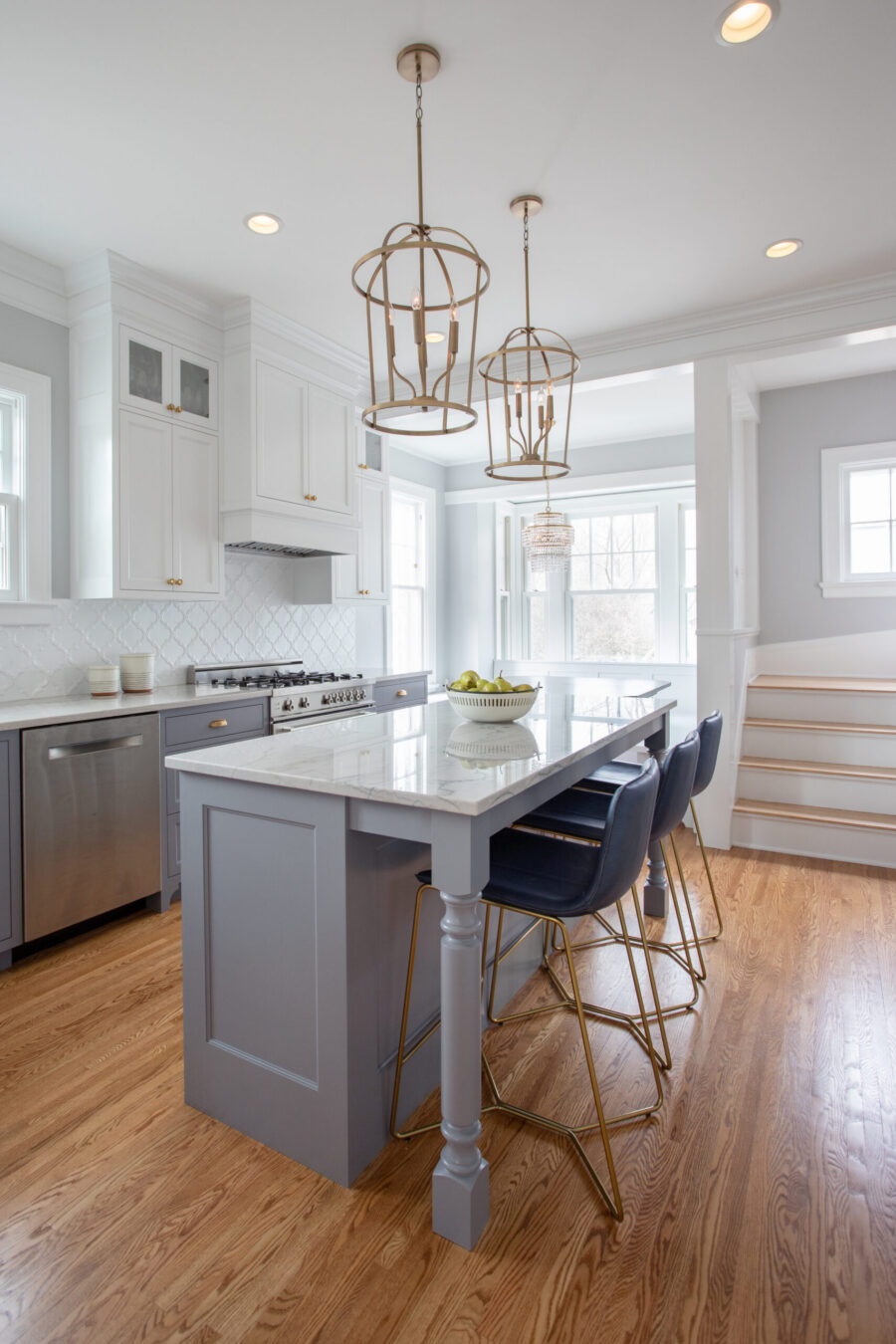 Twin Cities kitchen remodel features gray and white cabinets, marble island, and hardwood floors. Brass pendants illuminate.