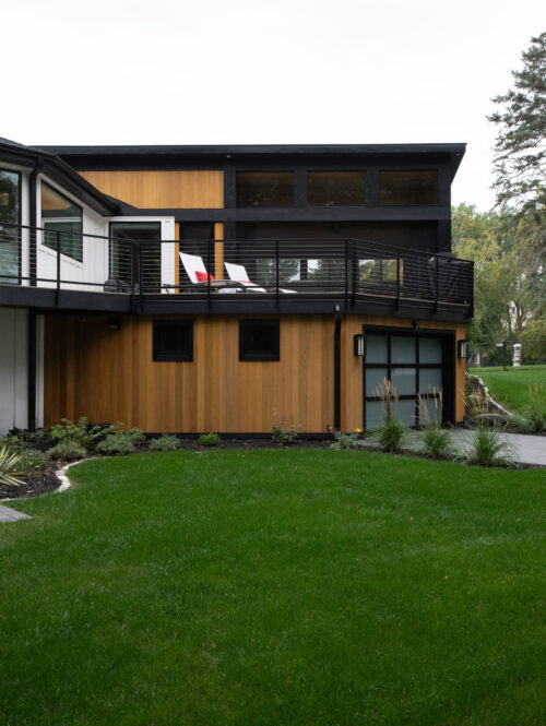 Contemporary design-build features prominent timber panels, dark trim, large deck.