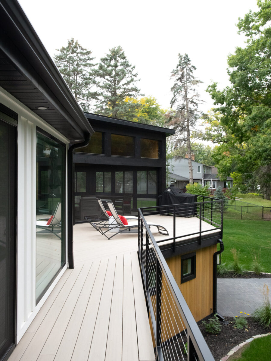 Expansive contemporary home renovation delivers light composite decking, black railing.