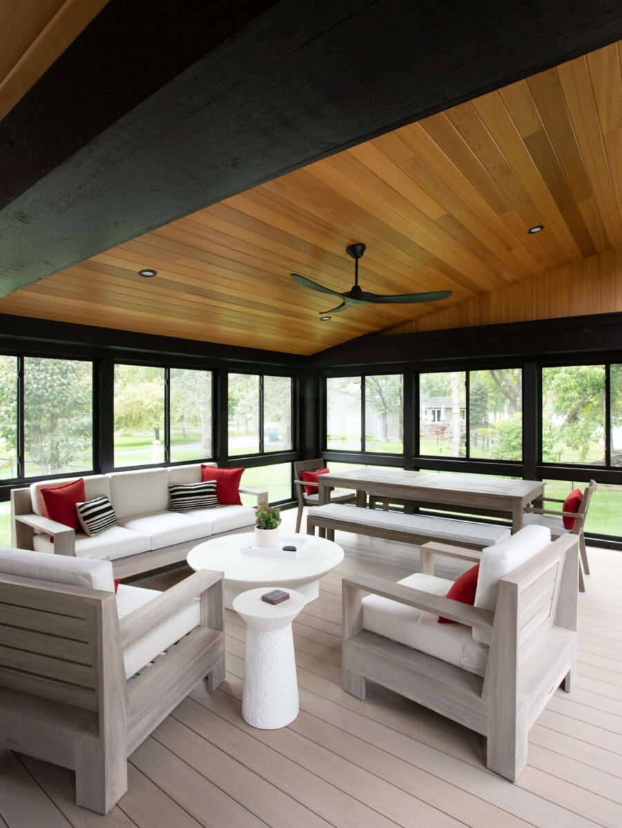 Modern Twin Cities sunroom design features a wood plank ceiling, dark window frames, and light grey outdoor furniture.