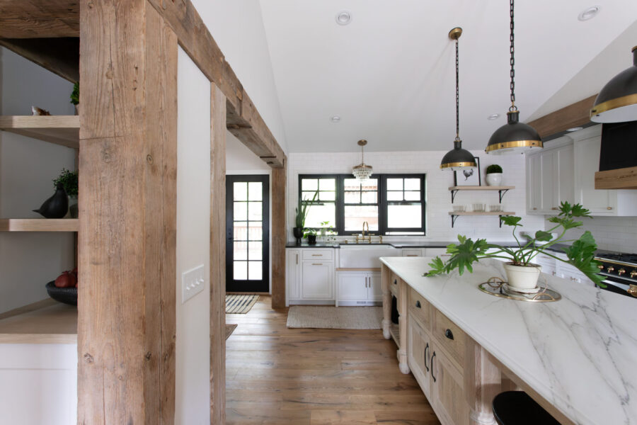 Rustic wood beams frame this modern Twin Cities kitchen remodel, with a large marble island and black windows.