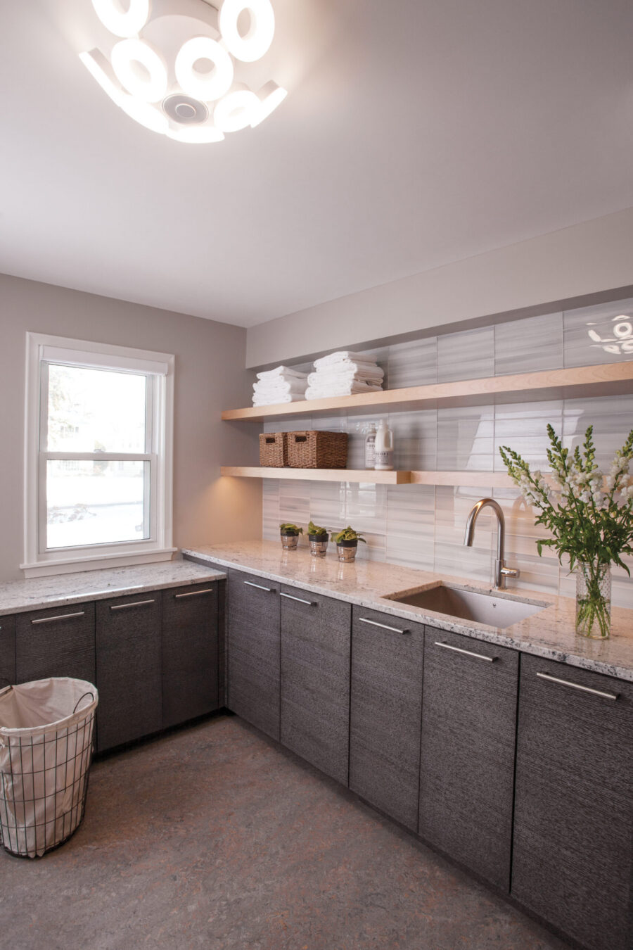 Twin Cities modern laundry room remodel with dark cabinets, granite, floating shelves.