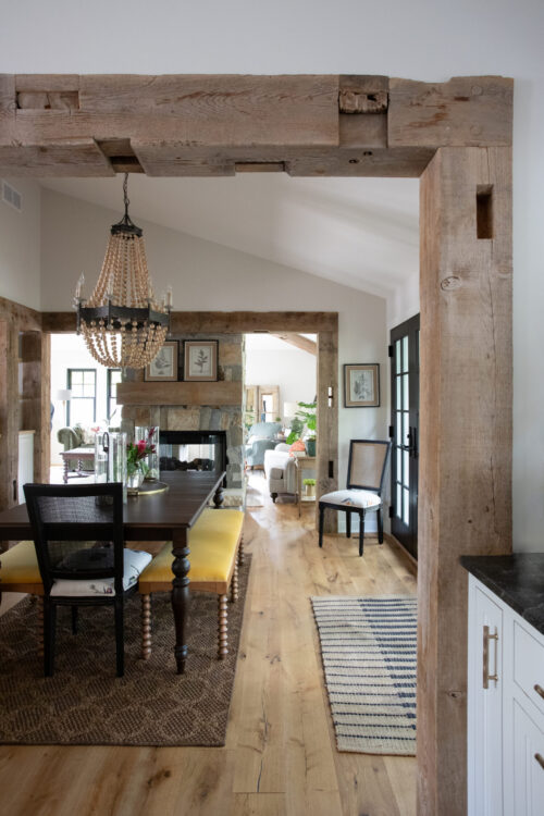 Exposed timbers frame Twin Cities open-concept home remodel; stone fireplace.
