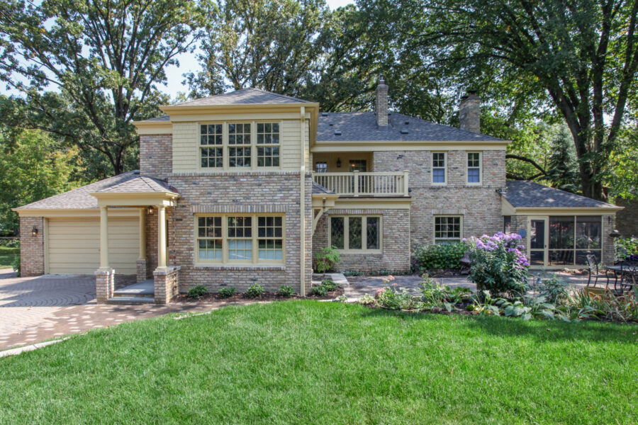 Stately two-story light brick home features warm trim, lush landscaping. Premier home renovation.