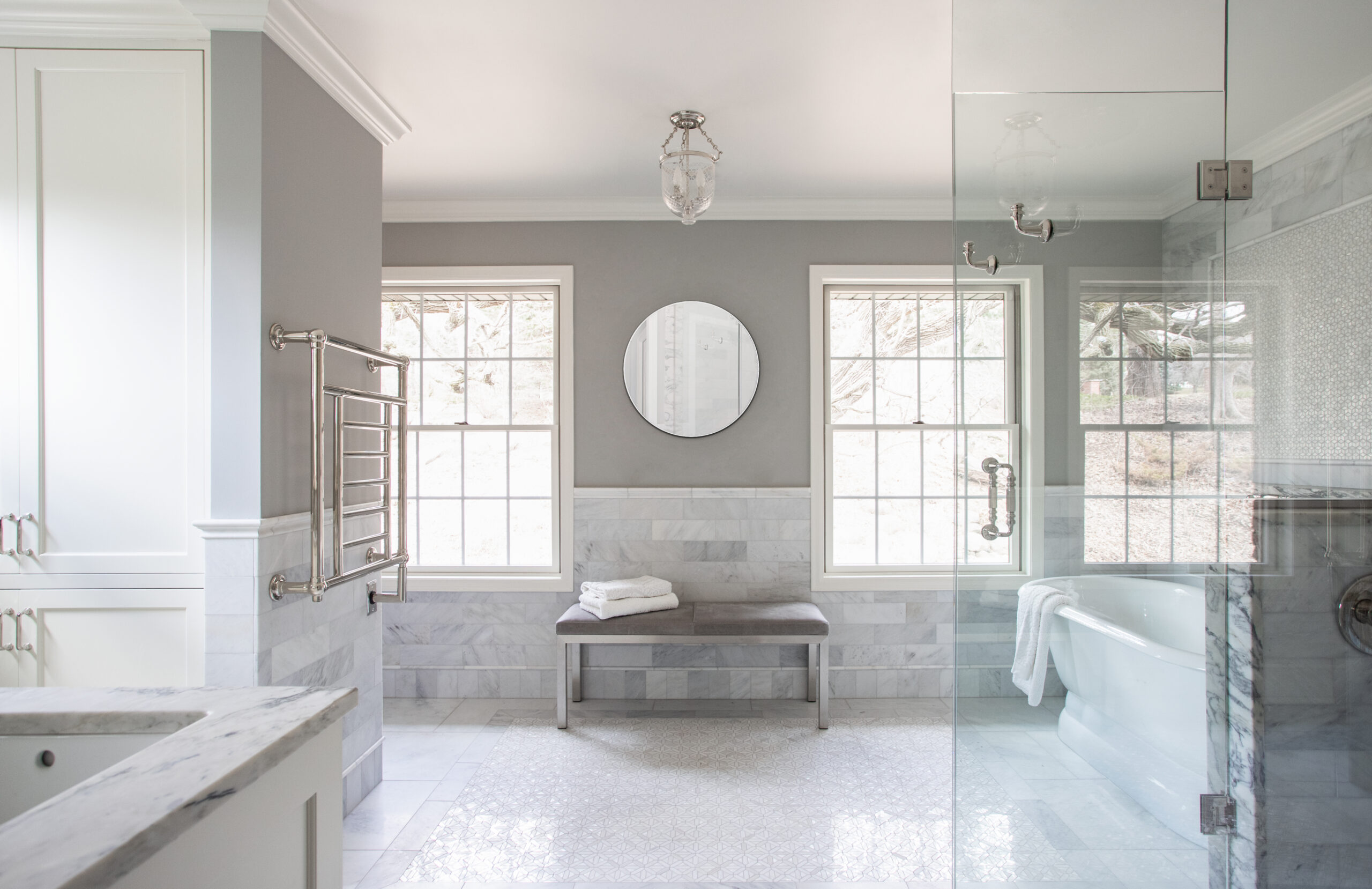 Luxurious bathroom remodel integrates polished marble, plentiful natural light, glass enclosure.