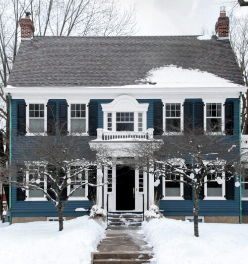 blue siding exterior remodel highlights classic home architecture with bright white trim in winter snow