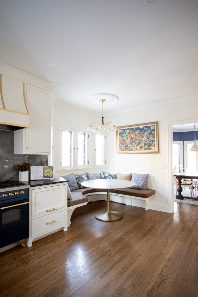 Twin Cities kitchen renovation: white cabinets, blue stove, marble backsplash, bay window banquette, hardwood.