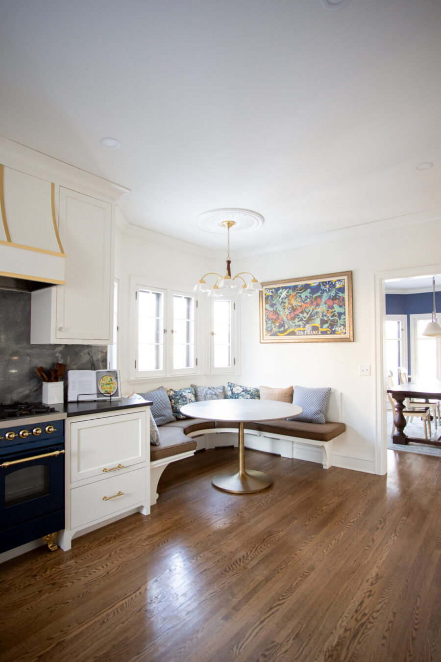 Twin Cities kitchen renovation: white cabinets, blue stove, marble backsplash, bay window banquette, hardwood.