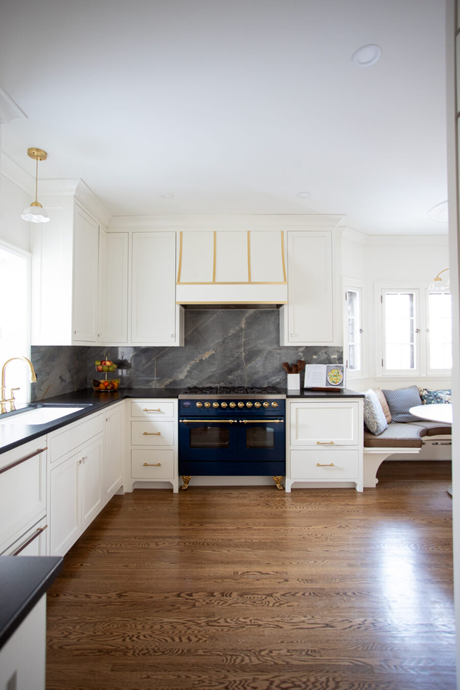 Bright Twin Cities kitchen remodel features white shaker cabinets, a striking blue range, and dark marble backsplash.