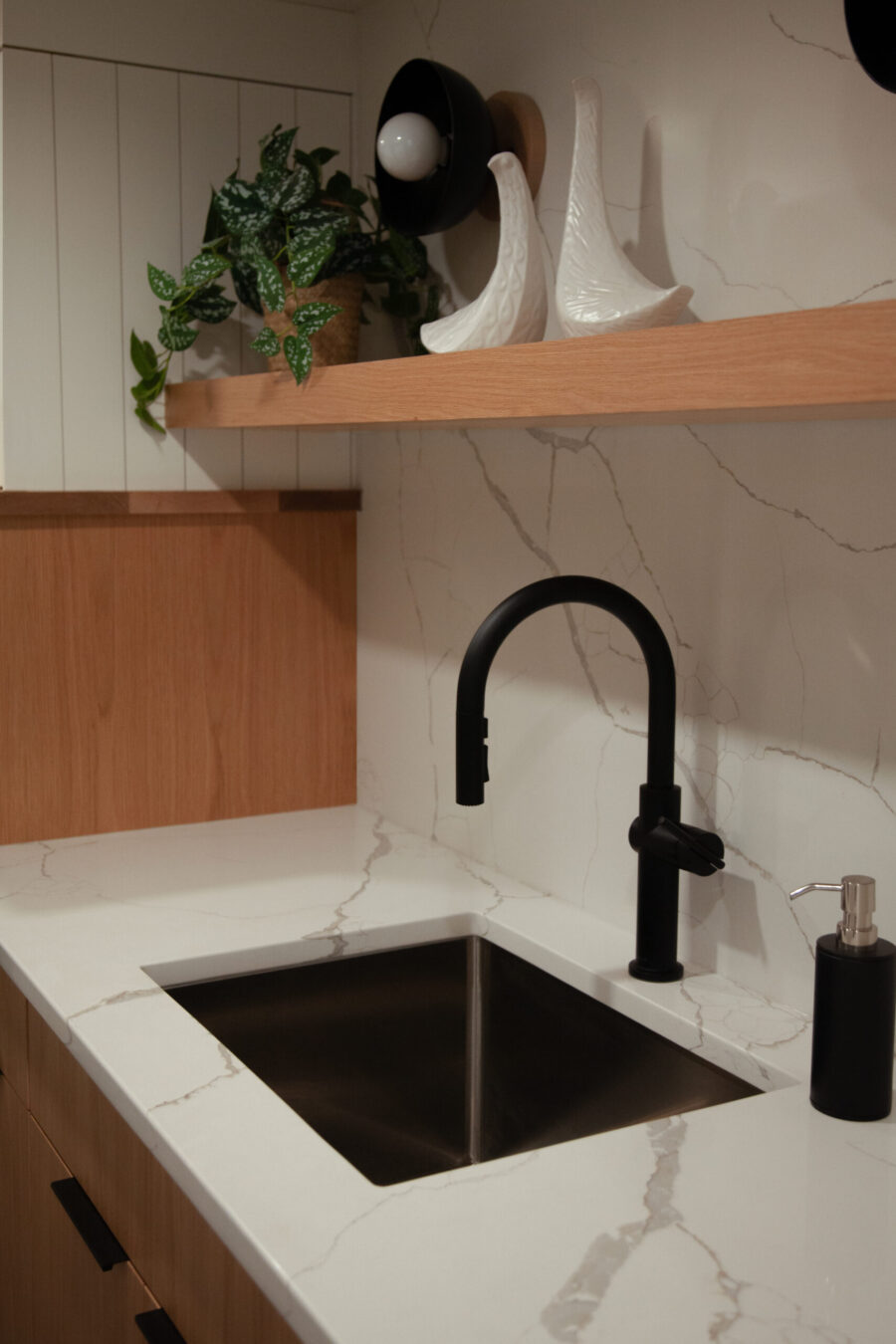 Modern Twin Cities kitchen remodel features white quartz, a black faucet, and light wood cabinetry.
