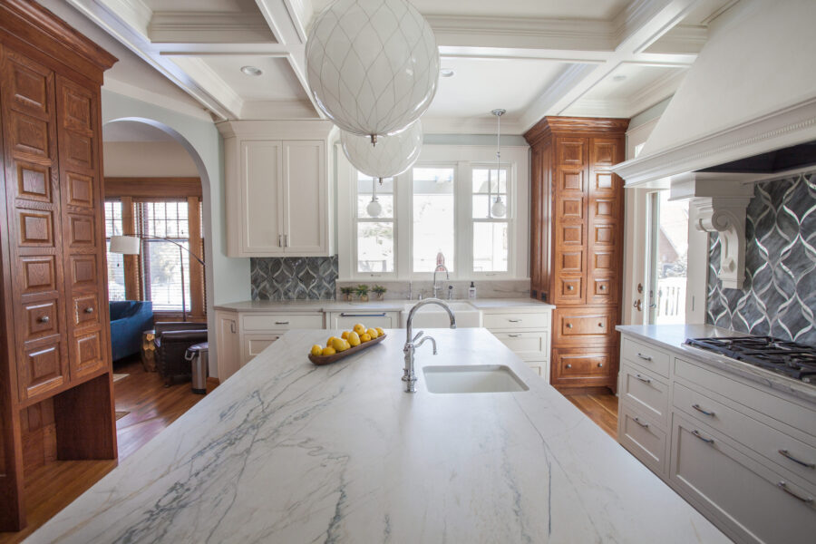 Twin Cities kitchen features marble island, white cabinets, dark wood pantry, and a coffered ceiling.