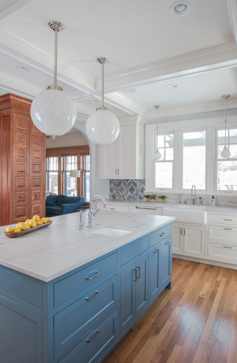 Kitchen remodel combines blue island, white perimeter, warm wood flooring.