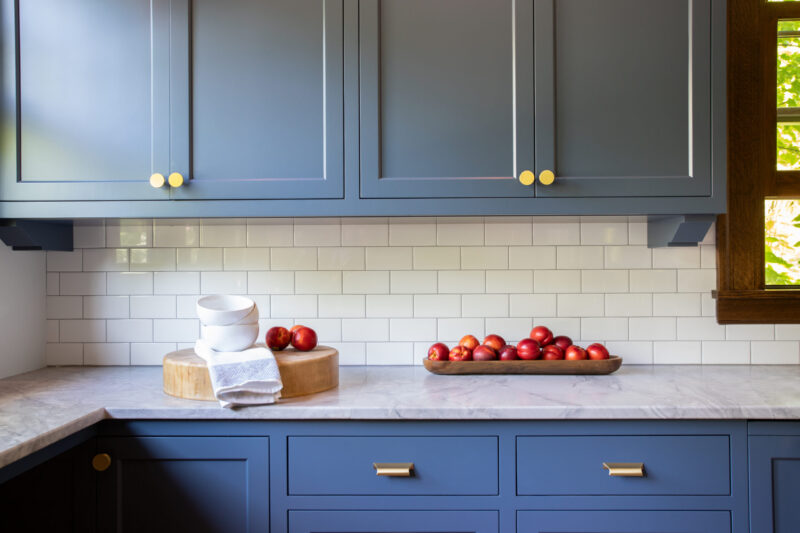 Twin Cities kitchen remodel boasts blue cabinetry, white tile, marble counters.
