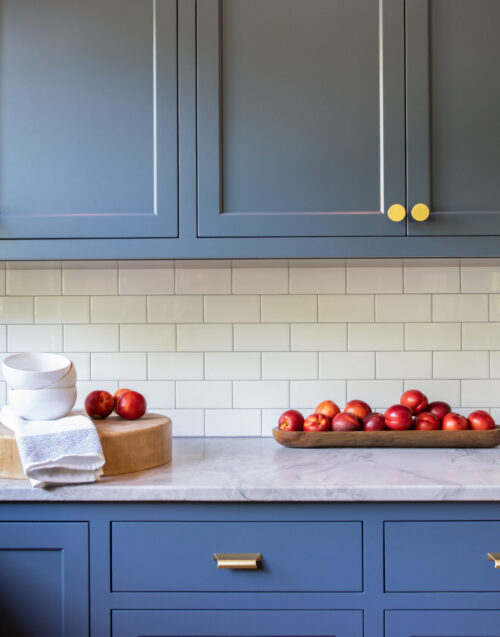 Twin Cities kitchen remodel boasts blue cabinetry, white tile, marble counters.