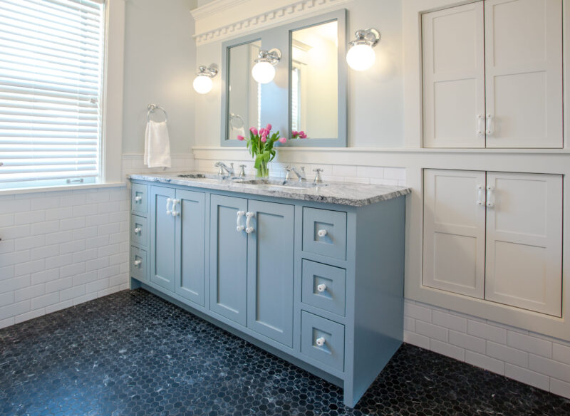 Twin Cities bathroom remodel: light blue vanity, black hexagon floor, white subway tile.