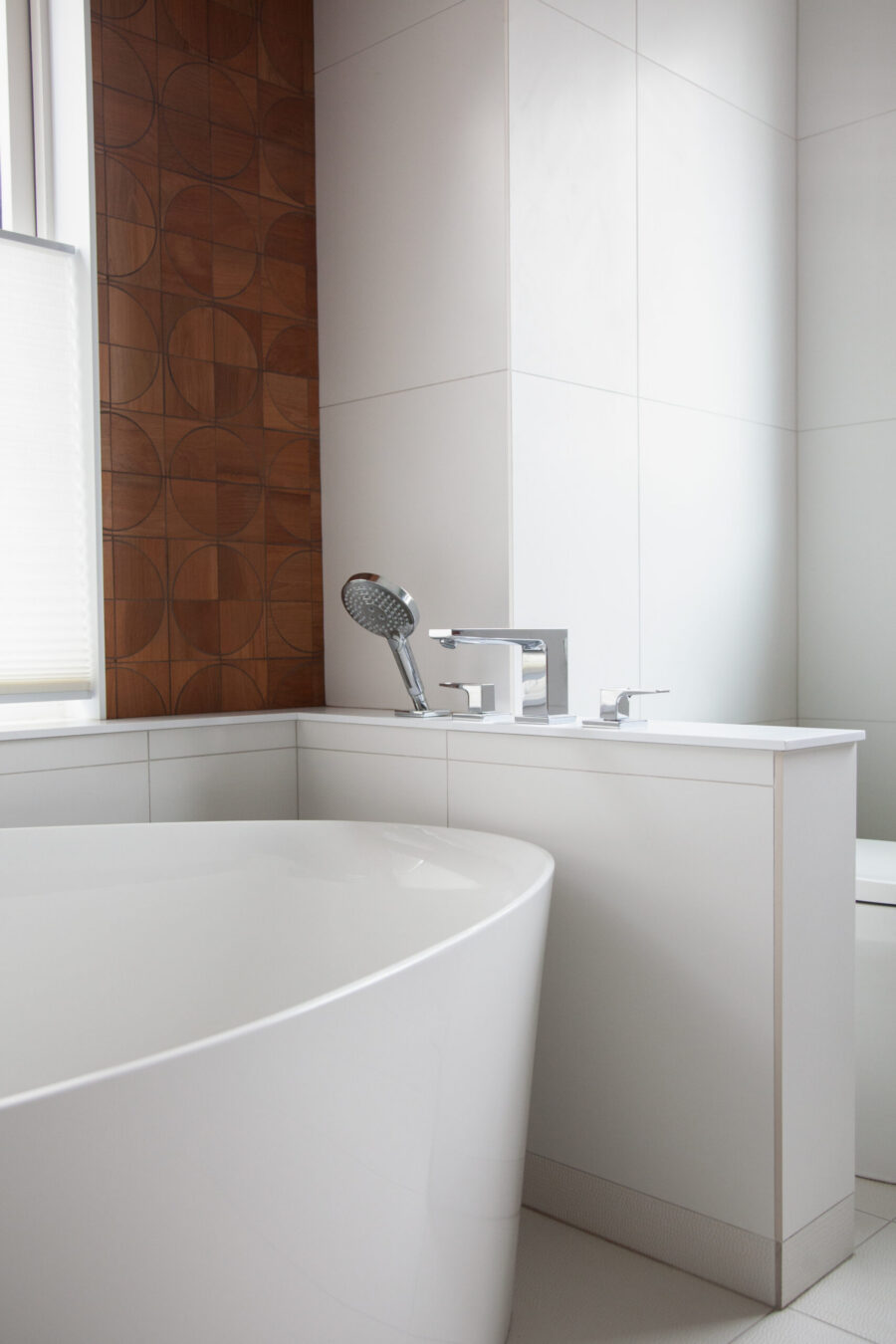 Modern Twin Cities bathroom remodel features white freestanding tub, decorative wood paneling.