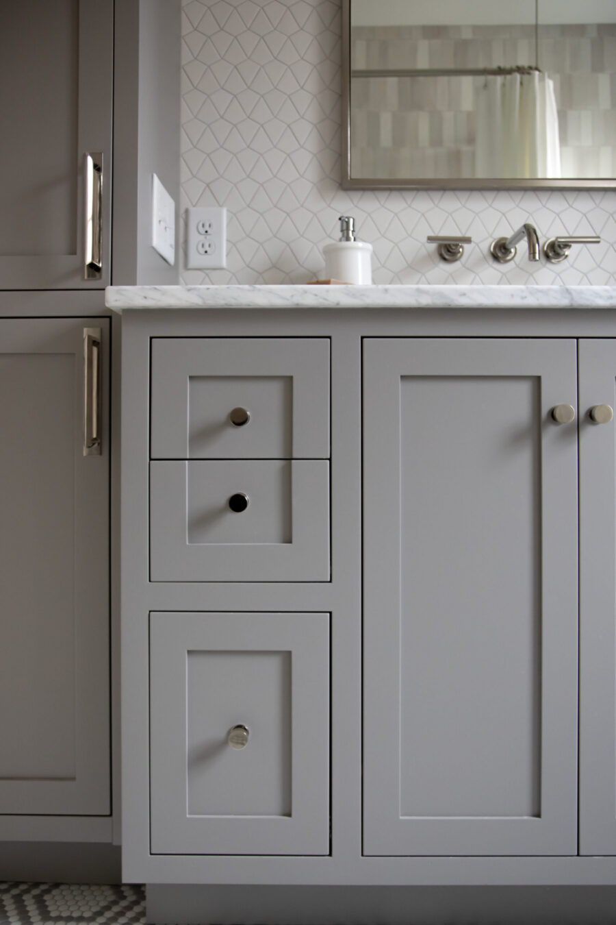 Sophisticated Twin Cities bathroom remodel displays gray cabinetry, marble, patterned backsplash.