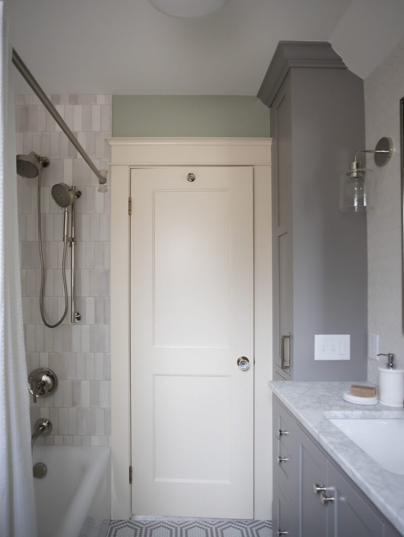 Remodeled Twin Cities bathroom features gray vanity, marble, white subway tile shower.