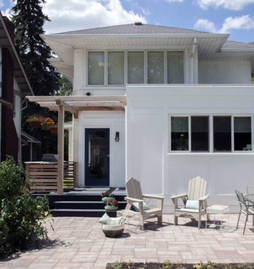 Architectural contemporary exterior renovation incorporates expansive paver patio, pergola.