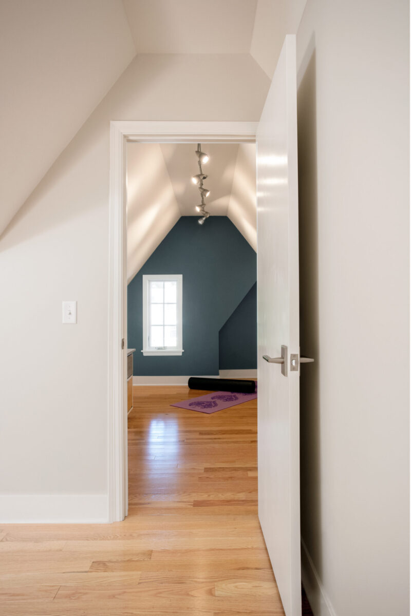 Twin Cities home renovation reveals bright hardwood, sloped walls, track lights.