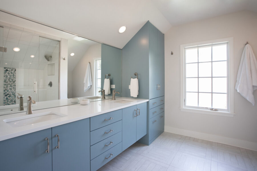 Twin Cities bathroom renovation features blue vanity, white quartz, and a glass shower.