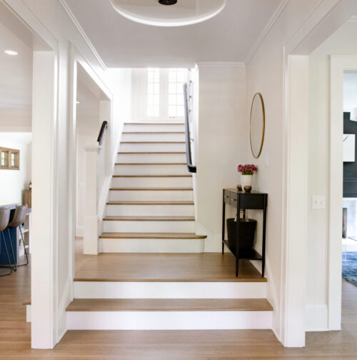 Bright Twin Cities kitchen remodel features a prominent blue island and light wood cabinetry, flowing into an open staircase.