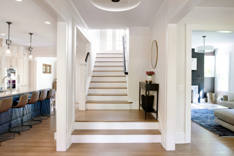 Bright Twin Cities kitchen remodel features a prominent blue island and light wood cabinetry, flowing into an open staircase.