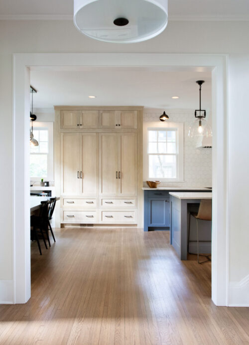 Twin Cities kitchen remodel features light wood cabinetry, a blue island, hexagon backsplash, and hardwood floors.