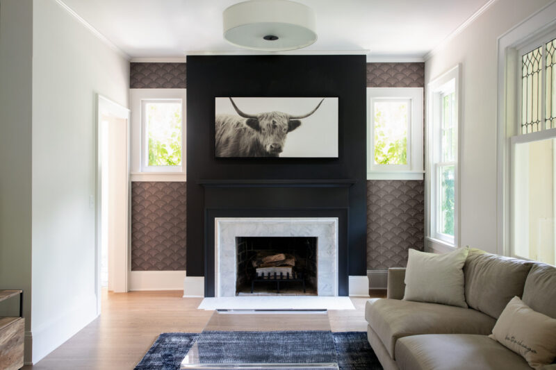 Twin Cities renovation offers a dark fireplace, white marble, brown wallpaper, and wood floor.