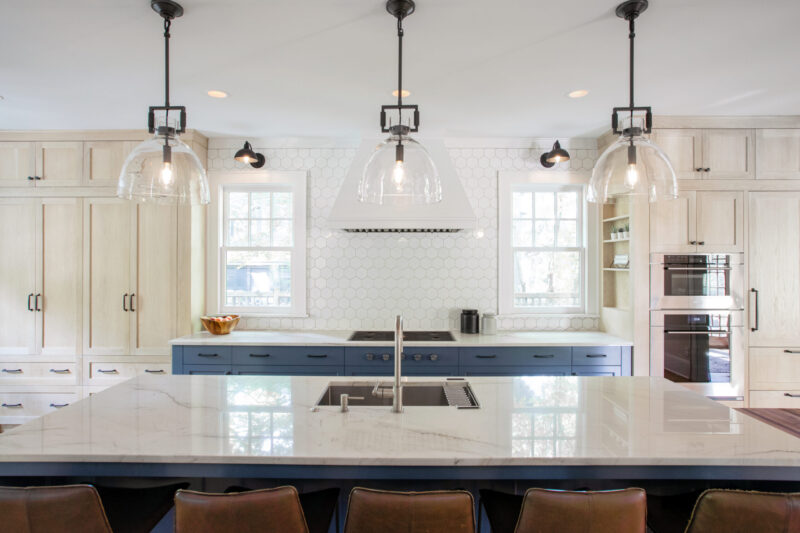 Twin Cities kitchen remodel boasts a marble island, blue base cabinets, light wood uppers, and a hexagonal tile backsplash.