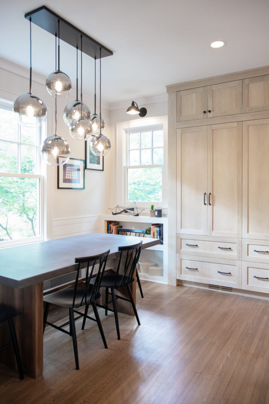 This Twin Cities renovation features modern dining design with extensive light wood storage and globe pendants.