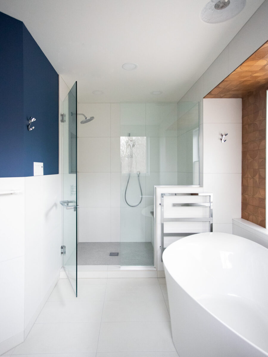 Contemporary bathroom renovation integrates freestanding tub, glass shower, azure and timber walls.