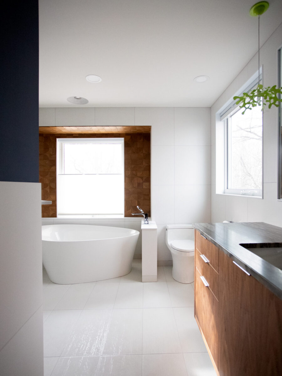 Twin Cities bathroom renovation features white tile, a freestanding tub, and a dark wood vanity.