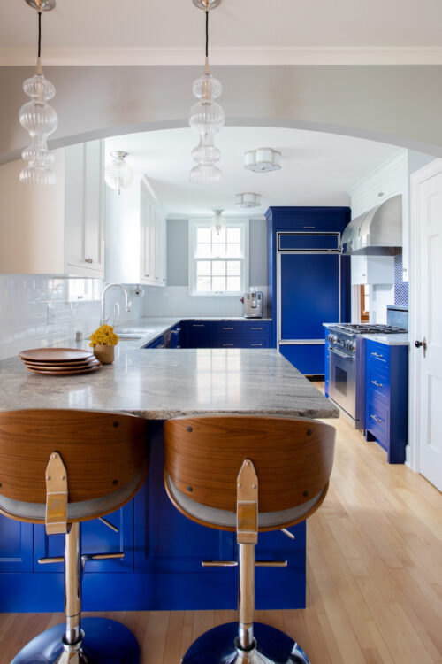 Contemporary blue-painted cabinetry offers granite-clad island and glass-pendant-lighting kitchen-remodel
