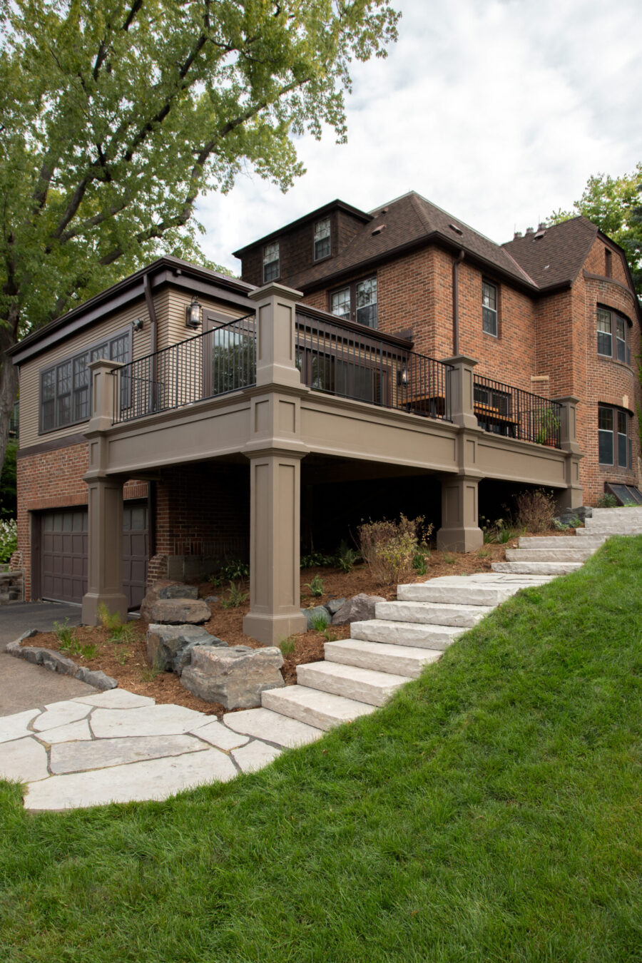 Residential exterior design build added elevated deck, stone stairs, and landscaping.