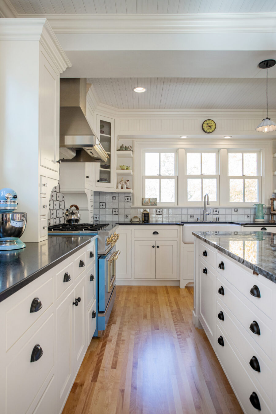 A Twin Cities kitchen remodel features white shaker cabinets, dark countertops, hardwood floors, and patterned tile backsplash.