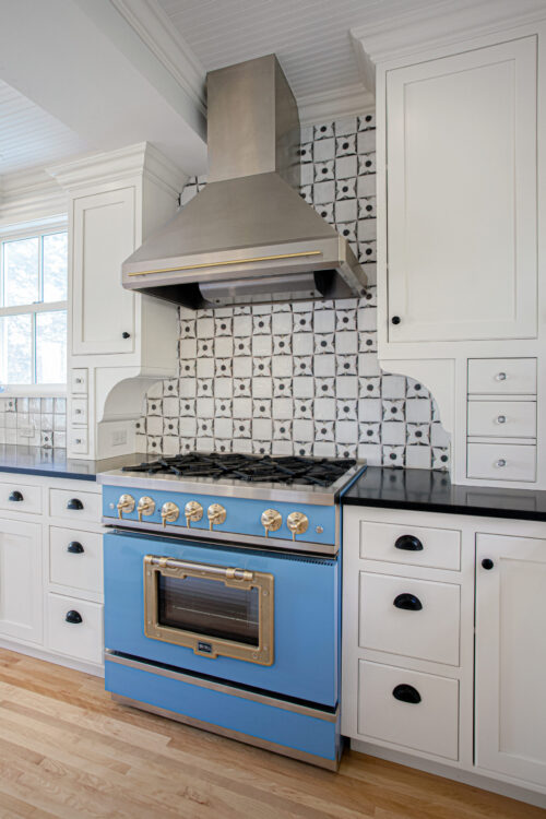Sky-blue professional-range anchors classic-shaker cabinetry and patterned-tile backsplash