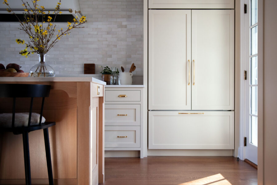 Bright kitchen features blonde island, white integrated refrigeration, and subway tile.