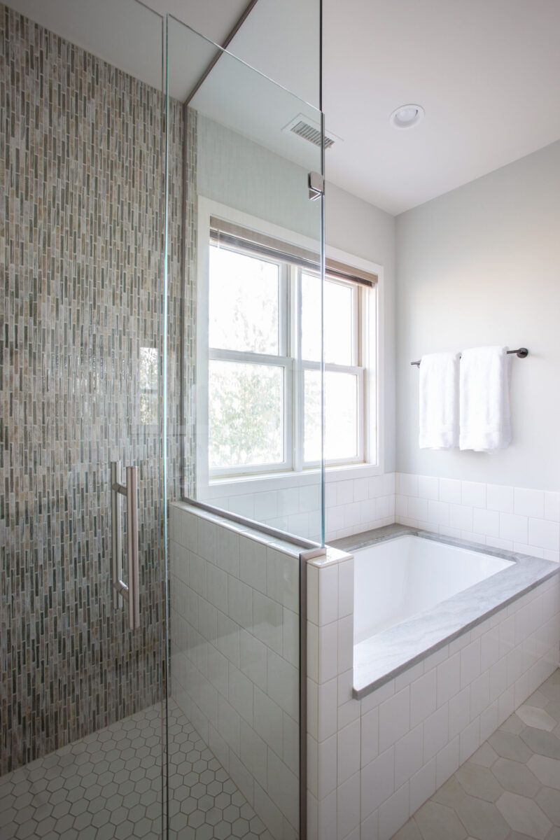 Modern Twin Cities bathroom renovation: glass shower, mosaic wall, soaking tub.