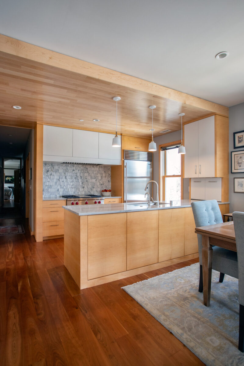Chic, modern Twin Cities kitchen remodel integrates light cabinetry, warm woods, marble backsplash.